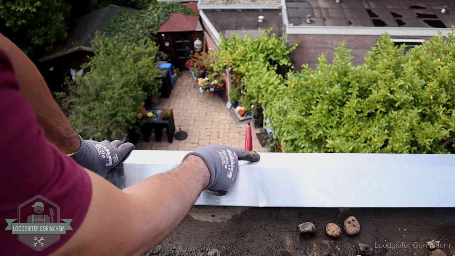 Vakman plaatst een daktrim op de dakrand van een woning in Gorinchem