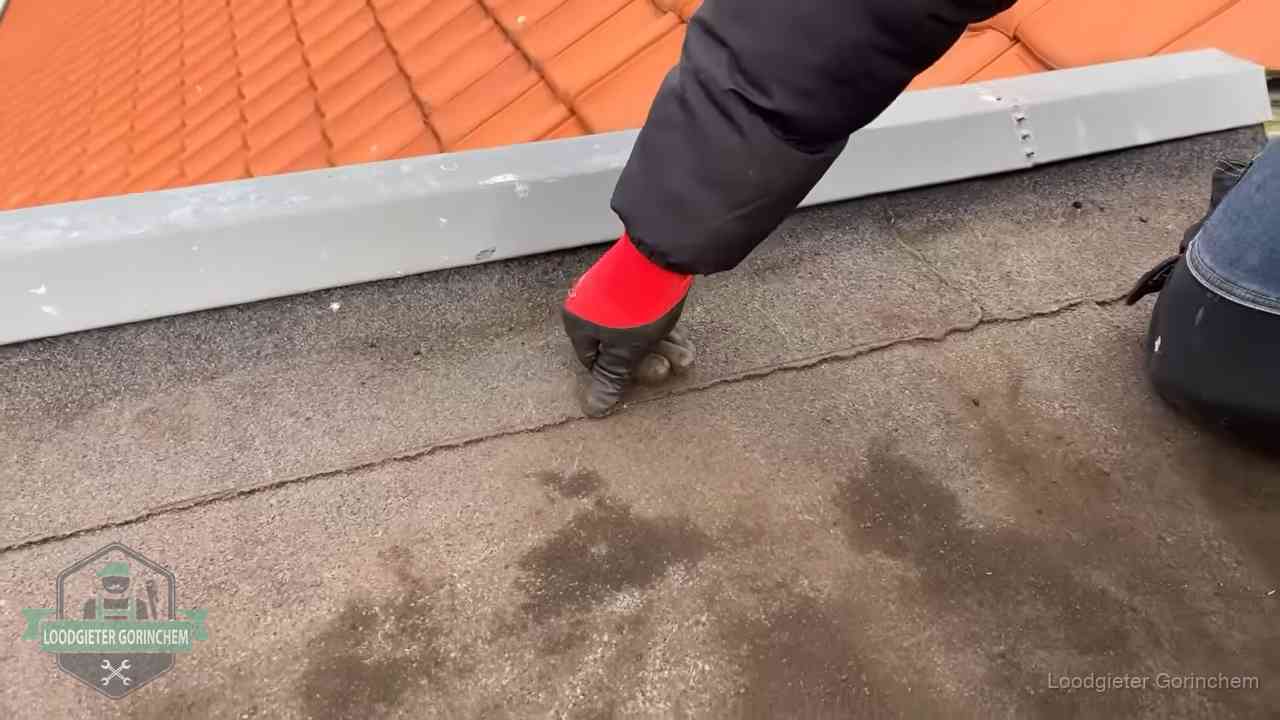 Vakman wijst een naad met vochtplekken aan op een bitumen plat dak in Gorinchem