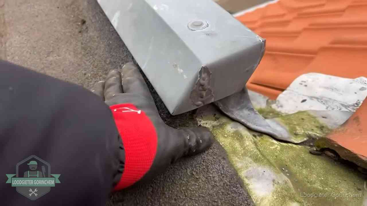 Controle van een zinken hemelwaterafvoer met loodslab bij dakpannen in Gorinchem