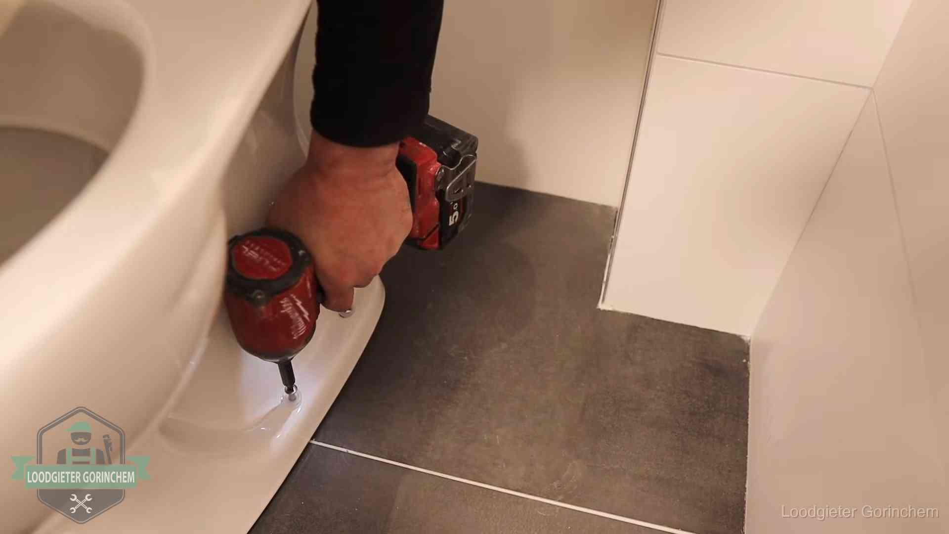 Kosten wc ontstoppen in Gorinchem Loodgieter zet de voet van een wc-pot vast op de tegelvloer in Gorinchem
